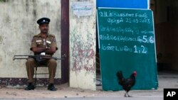 A Sri Lankan police officer guards outside a polling station before the beginning of voting in Jaffna, Sri Lanka, Saturday, Sept. 21, 2013.