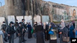 Warga Palestina menunggu untuk menyeberangi pos pemeriksaan Qalandia antara kota Ramallah Tepi Barat dan Yerusalem, untuk menghadiri salat Jumat pertama di masjid al-Aqsa, selama bulan suci Ramadan, Jumat, 16 April 2021. (AP Photo/Nasser Nasser)