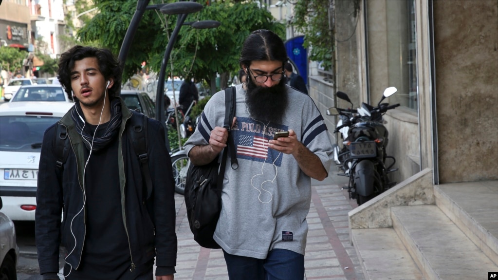 Un hombre usa su telÃ©fono celular mientras camina por el centro de TeherÃ¡n, IrÃ¡n. 18-4-18. 