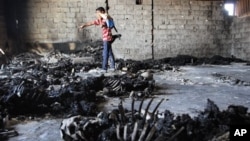 NOTE: GRAPHIC CONTENT - A rebel fighter walks inside a warehouse containing the remains of at least 50 burned bodies in Tripoli, Libya, Sunday, Aug. 28, 2011. A survivor said they were civilians killed by pro-Gadhafi soldiers.
