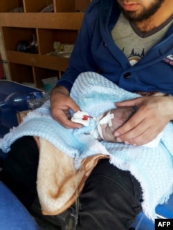 A man holds an injured baby inside a Turkish ambulance as injured Syrian people enter into Turkey from the Cilvegozu border gate in Hatay province, near the Syrian border, April 4, 2017. A suspected chemical attack occurred in northwestern Syria.