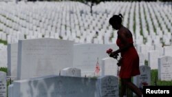 Une femme porte des fleurs sur une tombe pour Memorial Day au cimetière d'Arlington à Washington, DC, le 30 mai 2016.