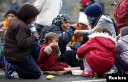 FILE - Migrants rest before crossing the Austrian-German border in Achleiten, Austria, across from Passau, Germany, Oct. 29, 2015.