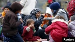 FILE - Migrants rest before crossing the Austrian-German border in Achleiten, Austria, across from Passau, Germany, Oct. 29, 2015.