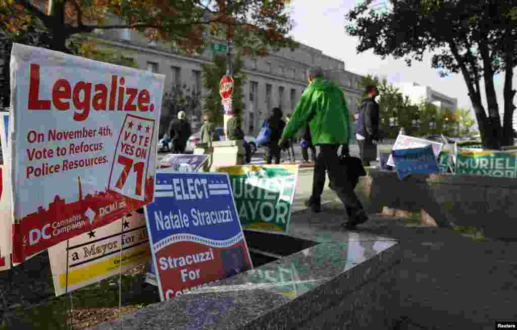 Pedestrians pass by a D.C. Cannabis Campaign sign in Washington, D.C., Nov. 4, 2014. Voters in the U.S. capital and two West Coast states will decide whether to legalize marijuana in a test for broader cannabis legalization efforts across the United States.