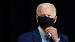 ish-Nënpresidenti Joe Biden duke hequr maskën përpara një fjalimi