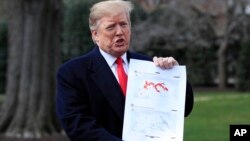 President Donald Trump shows a map of Syria and Iraq showing the presence of the Islamic State in 2017 and 2019, as he speaks to reporters before leaving the White House in Washington, March 20, 2019.
