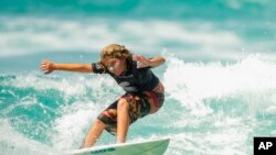 Ravi Hadat, de 11 anos, surfa em uma onda durante uma competição local de surfe em 27 de novembro de 2022 na costa de Maurício em São Sebastião, Brasil.