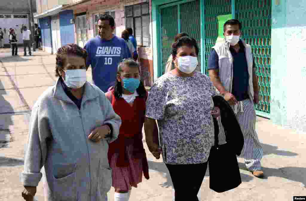 People wear face masks near the site of the tanker explosion in San Pedro Xalostoc, May 7, 2013.