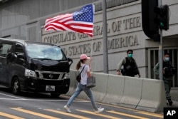 资料照：在美国驻港澳总领事馆外的一次抗议活动中一名抗议者举着一面美国国旗过马路。（2020年7月4日）