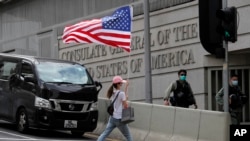 资料照：在美国驻港澳总领事馆外面的一次抗议活动中，一名抗议者举着一面美国国旗过马路。（2020年7月4日）
