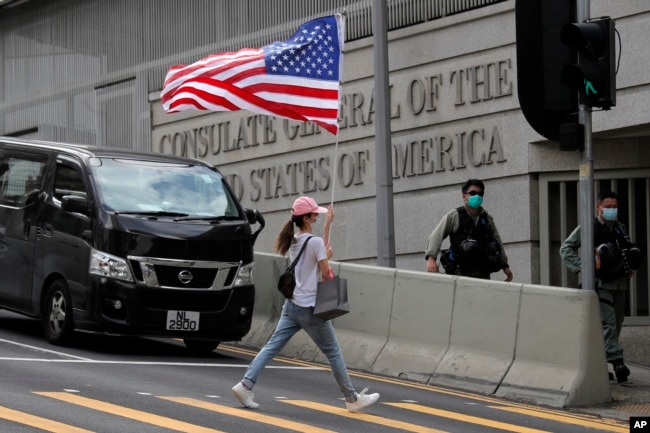 资料照：在美国驻港澳总领事馆外的一次抗议活动中一名抗议者举着一面美国国旗过马路。（2020年7月4日）