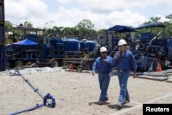 Workers walk past machinery at Miranda Port in Tiputini, Ecuador, Sept. 7, 2016.