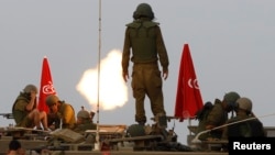 FILE - Israeli soldiers stand on an armored personnel carrier (APC) outside the central Gaza Strip as they fire mortar shell towards Gaza before a ceasefire was due, early Aug. 1, 2014. 