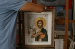 George Gavriel meletakkan sebuah lukisannya di easel di studionya di Kokkinotrimithia, Siprus, 15 Oktober 2021. (REUTERS/Yiannis Kourtoglou).