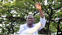 Uganda's Forum for Democratic Change leader Kizza Besigye waves to his supporters as he is blocked from driving to work in Kampala, prior to his arrest at gunpoint, April 28, 2011