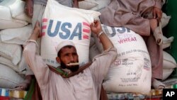 An Afghan refugee collects a bag of wheat being distributed by the World Food Program and USAID.