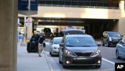 In this Dec. 18, 2019, file photo passengers find their rides at the Ride Share point as they exit Phoenix Sky Harbor International Airport in Phoenix. (AP Photo/Ross D. Franklin, File)