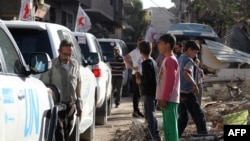Vehicles of the International Committee of the Red Cross (ICRC), the Syrian Arab Red Crescent and the United Nations wait on a street after an aid convoy entered the rebel-held Syrian town of Daraya, southwest of the capital Damascus, on June 1, 2016.