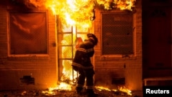 A firefighter uses a saw to open a metal gate while fighting a fire in a convenience store and residence during clashes after the funeral of Freddie Gray in Baltimore, Maryland, April 28, 2015. 