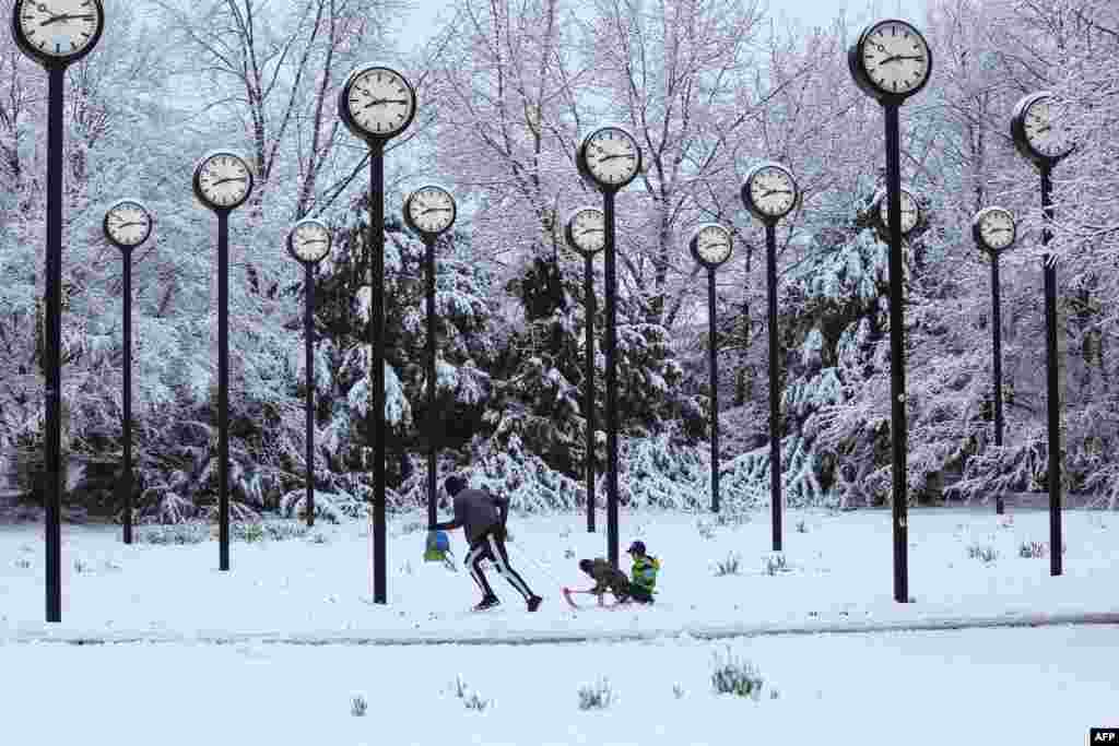 A man pulls children on a sledge through the snow-covered clock park by artist Klaus Rinke made of 24 station clocks, in Düsseldorf, western Germany.