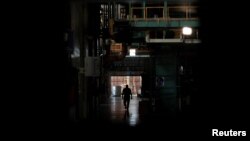 A worker walks next to halted machines at a cans' factory during a power cut in Valencia, Venezuela, April 8, 2019. 