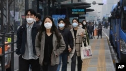 People wearing masks to protect from air pollution walk at a bus station in Seoul, South Korea, Wednesday, March 6, 2019. (AP Photo/Ahn Young-joon)