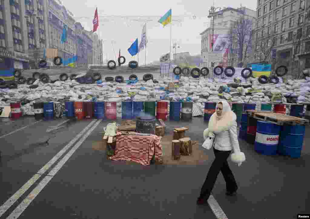 A woman walks near a barricade in Independence Square in Kyiv, Dec. 18, 2013.