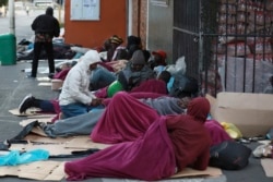 Refugees sleep on a sidewalk in Cape Town, South Africa, Friday, March 27, 2020, after South Africa went into a nationwide lockdown for 21 days in an effort to mitigate the spread to the coronavirus. (AP Photo/Nardus Engelbrecht)