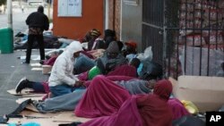 FILE: Refugees sleep on a sidewalk in Cape Town, South Africa, Friday, March 27, 2020, after South Africa went into a nationwide lockdown for 21 days in an effort to mitigate the spread to the coronavirus. (AP Photo/Nardus Engelbrecht)