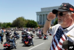 FILE - Ken Caryl of Dale City, Virginia salutes the motorcyclists, many of them are veterans, as they ride across the Memorial Bridge into Washington during the annual Rolling Thunder "Ride for Freedom," May 26, 2013.