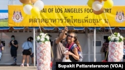 A couple takes a selfie in front of the Wat Thai of Los Angeles Food Court at Wat Thai (Thai Temple) of Los Angeles, North Hollywood, CA. November 06, 2021.