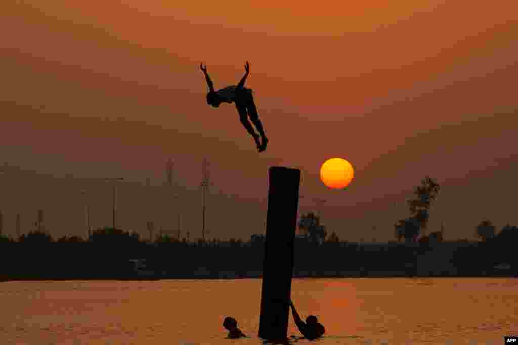 An Iraqi youth swims in the Shatt Al-Arab river by the port of Maqil amid a heatwave in the southern city of Basra, June 29, 2021.