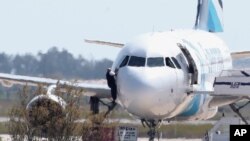 Un homme sort de l'avion détourné d'Egyptair depuis la fenêtre du cockpite à l'aéroport de Larnaca à Chypre le 29 mars 2016.