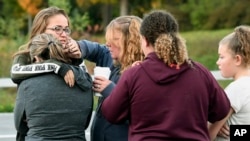Friends of victims who died in Saturday's fatal limousine crash comfort each other after placing flowers at the intersection in Schoharie, New York, Oct. 7, 2018. 