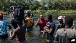 FILE - Migrants wade through the Rio Grande as they move from Ciudad Acuña, Mexico, into Del Rio, Texas, Sept. 19, 2021. 