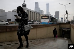 Residents walk out of a subway station near the central business district in Beijing Monday, March 9, 2020. With almost no new COVID-19 cases being reported in Beijing, workers are slowly returning to their offices with masks on and disinfectant in hand.