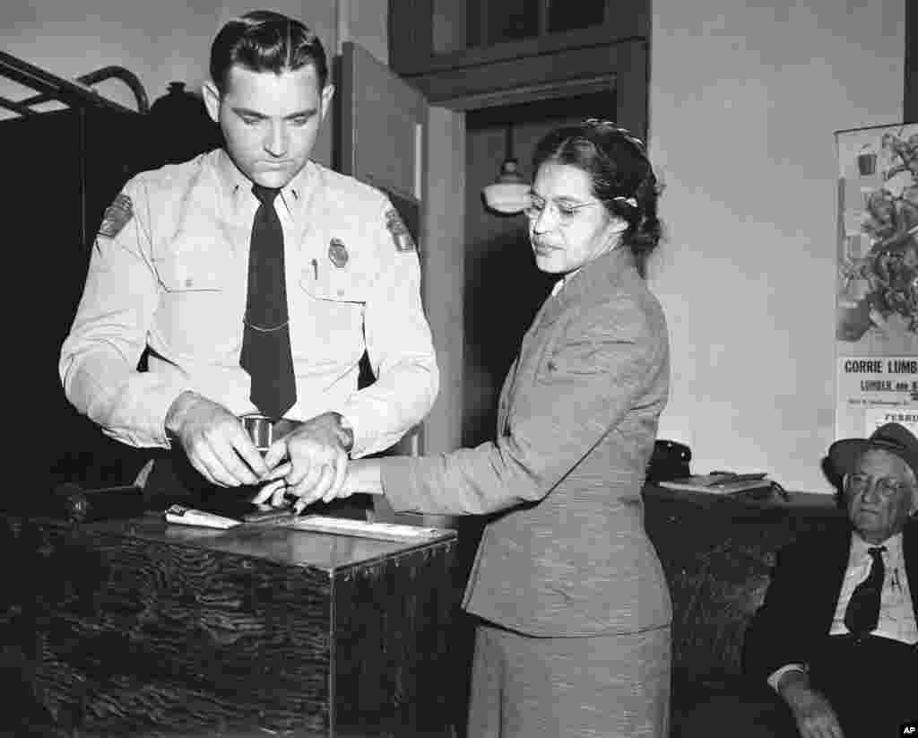 Rosa Parks, yang menolak pindah ke bagian belakang bus yang dikhususkan untuk warga kulit hitam, diambil sidik jarinya oleh polisi Lt. D.H. Lackey di Montgomery, Alabama, 22 Februari 1956. ​(AP/Gene Herrick)