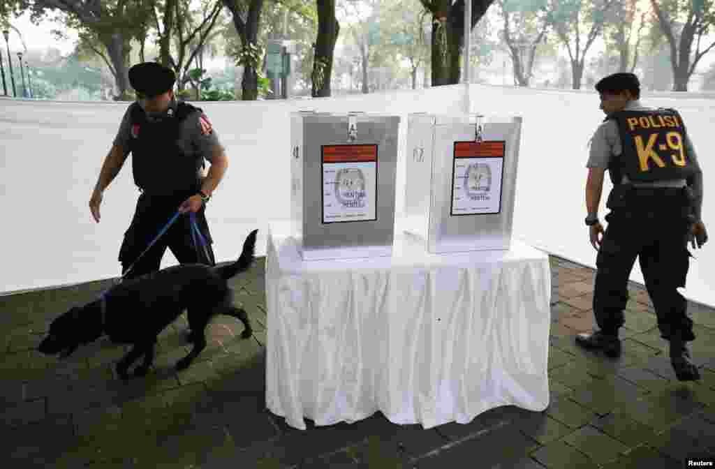 Polisi menggunakan anjing pelacak memeriksa TPS Taman Surapati, tempat kandidat presiden Joko &quot;Jokowi&quot; Widodo dan istrinya Iriana akan memilih (9/7).&nbsp;(Reuters/Darren Whiteside)