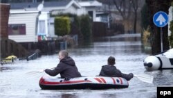 De jeunes garçons rament sur un bateau pneumatique le long d'une rue inondée à Kerkdriel, Pay-Bas,13 Janvier 2011. EPA / WIM Hollemans