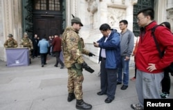 An Alpini Regiment of the Italian Army checks visitors outside the Milan's cathedral, northern Italy, Nov. 20, 2015. Italy and Sweden increased security around public buildings after receiving reports that attacks might be planned on their soil.