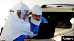 Nhân viên y tế mặc đồ bảo hộ xử lý các mẫu xét nghiệm COVID-19 tại một địa điểm xét nghiệm ngồi trong xe ở Sioux Falls, bang South Dakota, ngày 28 tháng 10, 2020.