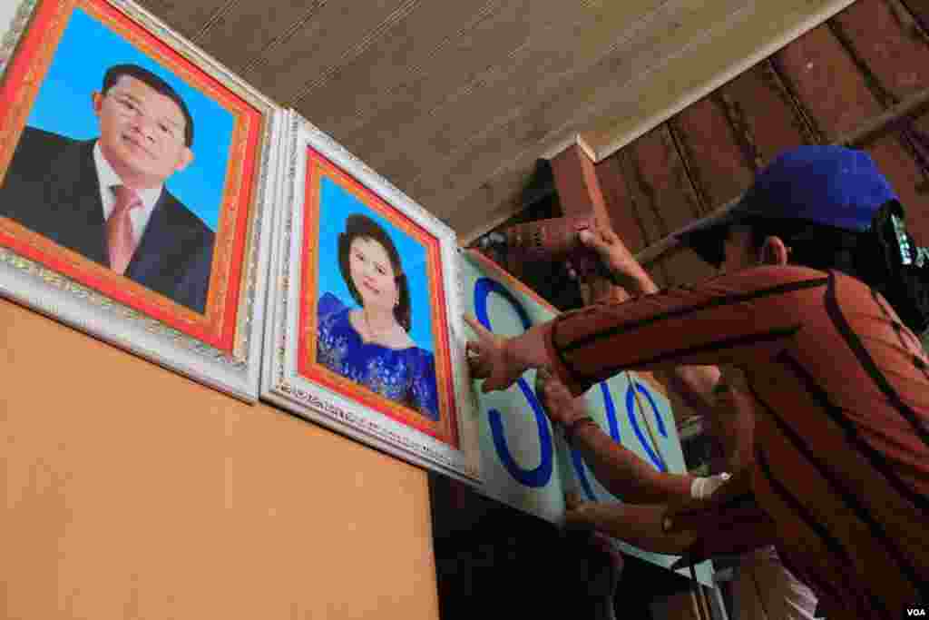 People in Tropeang Lavear display SOS messages next to the photo of Prime Minister Hun Sen and his wife Bun Rany on their wall, Cambodia, November 13, 2014. (Nov Povleakhena/VOA Khmer)