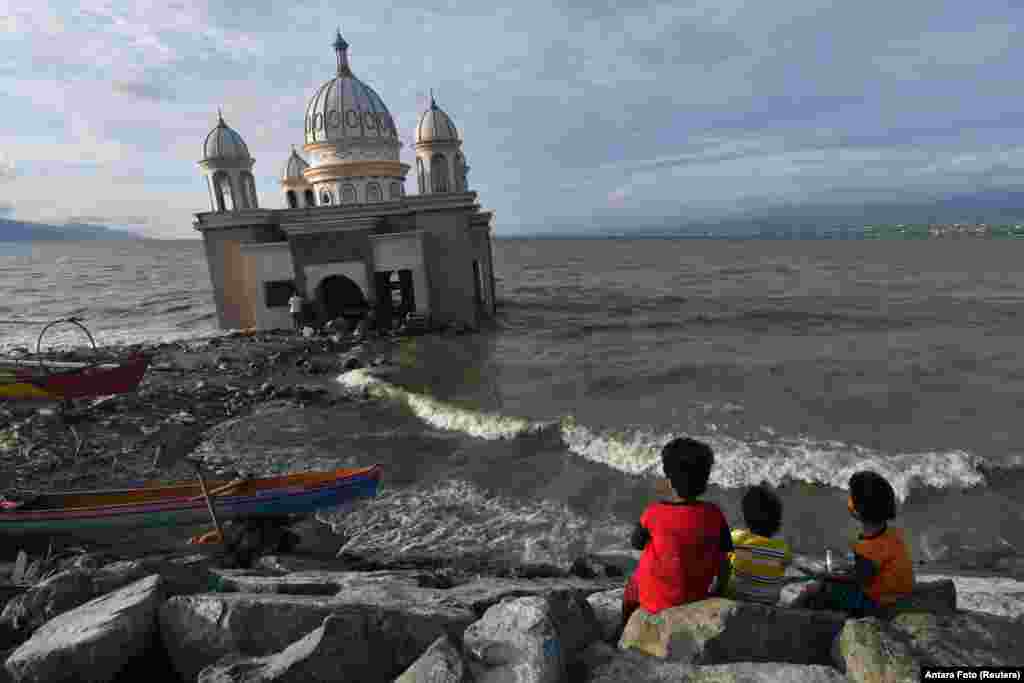 Children sit near a mosque as they wait to break the fast during the holy fasting month of Ramadan in Palu, Central Sulawesi Province, Indonesia.