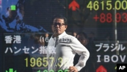 A man is reflected on the electronic board of a securities firm in Tokyo, Jan. 15, 2016. Asian stock markets were mixed Friday as investors were reluctant to return to risky assets despite ebbing fear about the Chinese currency devaluations and Wall Stree