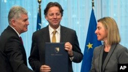 Chairman of the Presidency of Bosnia and Herzegovina Dragan Covic, left, Dutch Foreign Minister Bert Koenders, center, and European Union High Representative Federica Mogherini participate in a handover ceremony of the EU membership Application with Bosnia Herzegovina at the EU Council building in Brussels, Feb. 15, 2016.