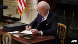ប្រធានាធិបតីសហរដ្ឋអាមេរិកលោក Joe Biden ចុះហត្ថលេខាលើបទបញ្ជានីតិប្រតិបត្តិមួយចំនួន នៅបន្ទប់ State Dinning Room ក្នុងសេតវិមាន រដ្ឋធានីវ៉ាស៊ីនតោន ថ្ងៃទី២១ ខែមករា ឆ្នាំ២០២១។