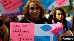 A transgender woman participates in a demonstration to commemorate U.N. International Day for the Elimination of Violence against Women in San Salvador, El Salvador, Nov. 25, 2016. The front sign reads: "Gender identity law now."