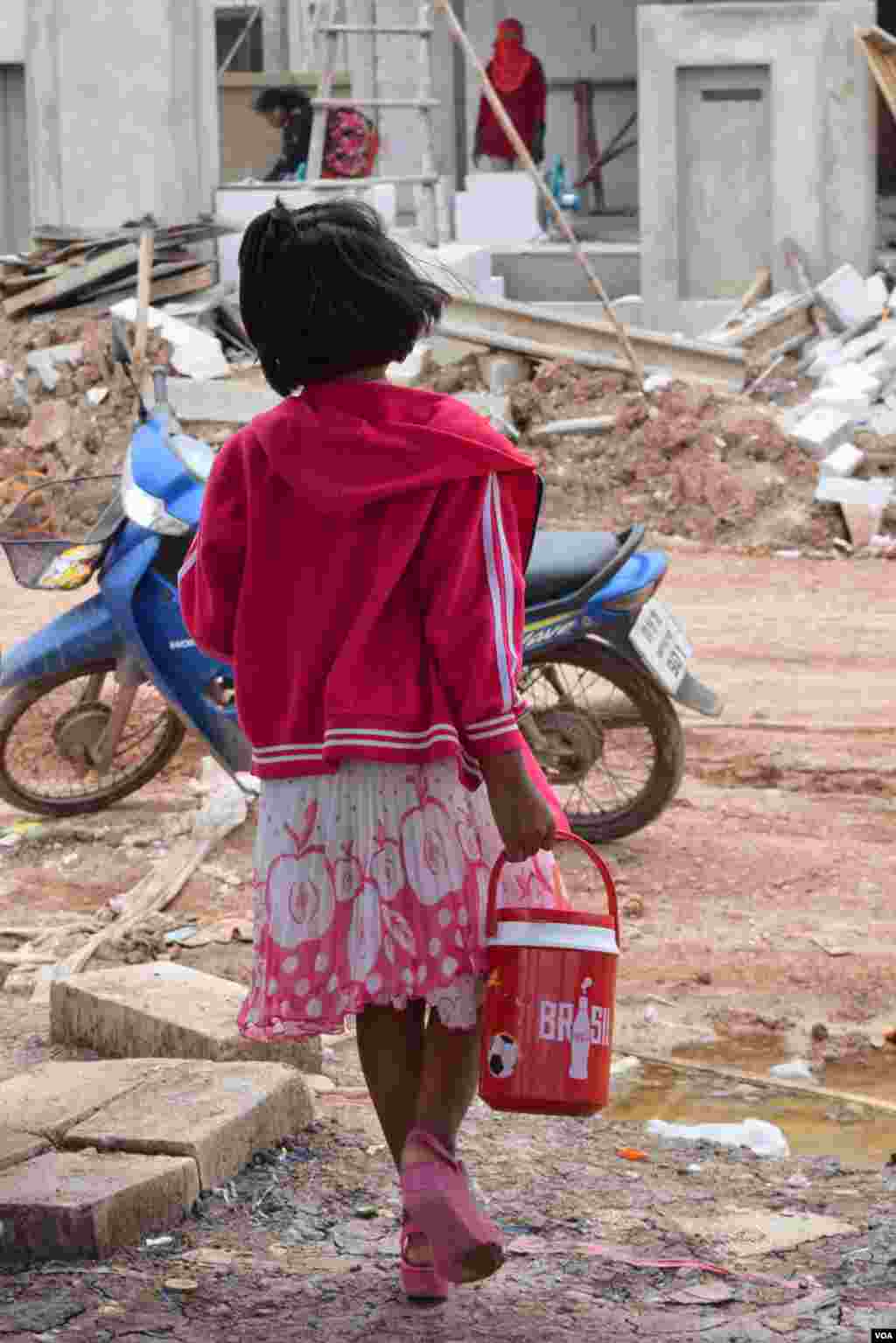 A girl goes on an errand at a construction site, Bangkok, July 10, 2014. (Rosyla Kalden/VOA)