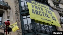 Greenpeace activists install banners in support of their detained colleagues on the front wall of Russia's Gazprom offices in Paris October 9, 2013.